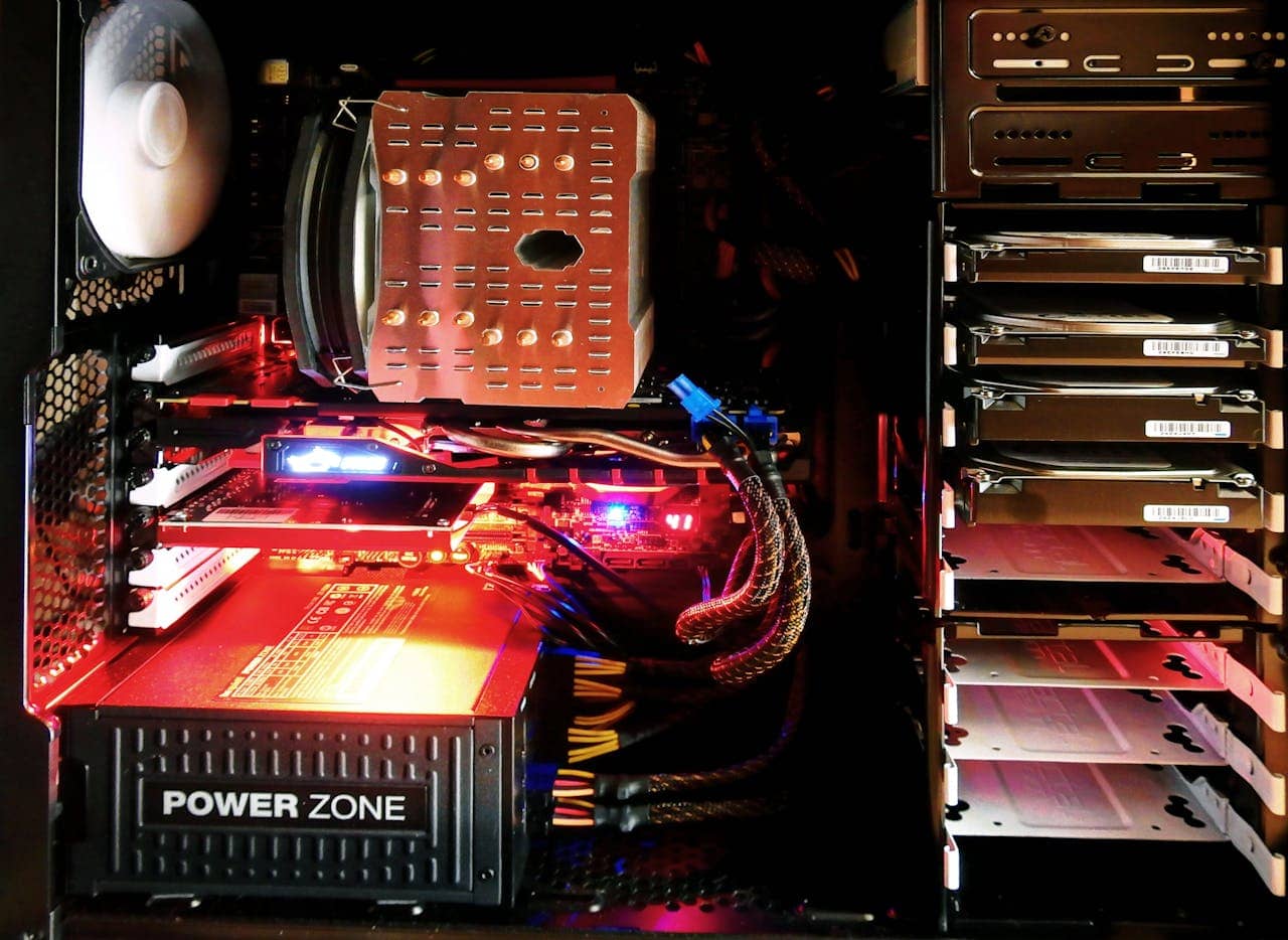 The inside of a desktop computer case is shown with a Power Zone power supply, cooling fan, motherboard, cables, and multiple hard drives installed.